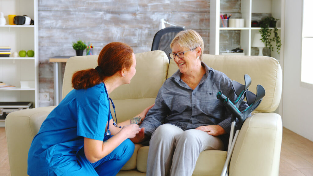 weibliche Pflegekraft übernimmt die häusliche Krankenpflege einer älteren Dame mit Krücken