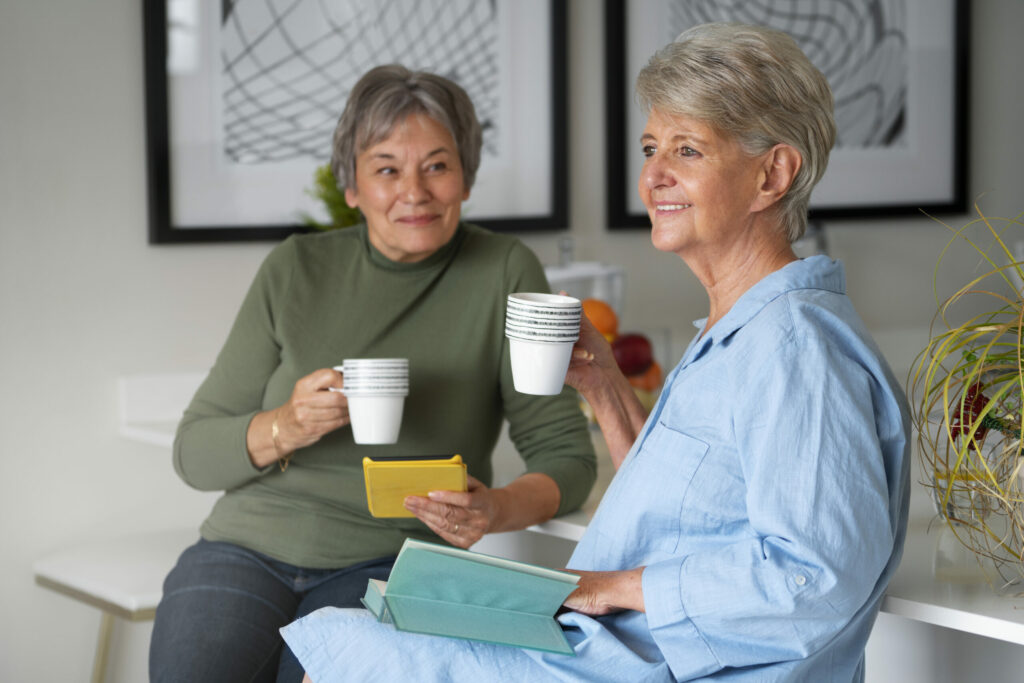 zwei Seniorinnen genießen die Seniorenbetreuung bei einer Tasse Kaffee